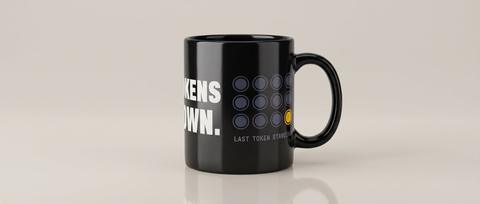 Tokens Down mug in Black. Fitted mockup. Printed on the wrap: TOKENS / DOWN. / LAST TOKEN STANDING.